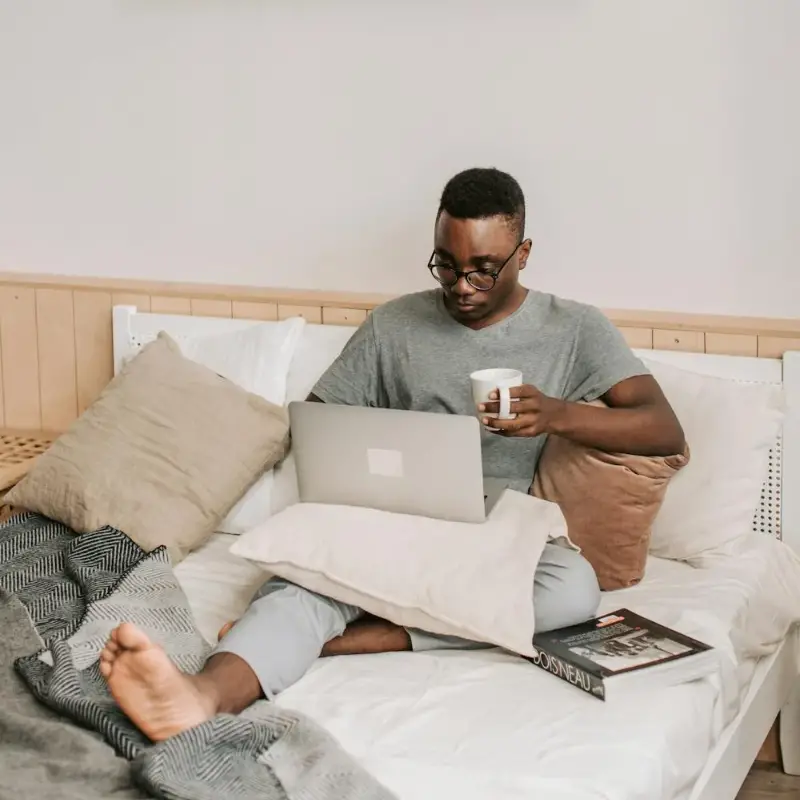 man-sitting-in-bed-with-his-laptop