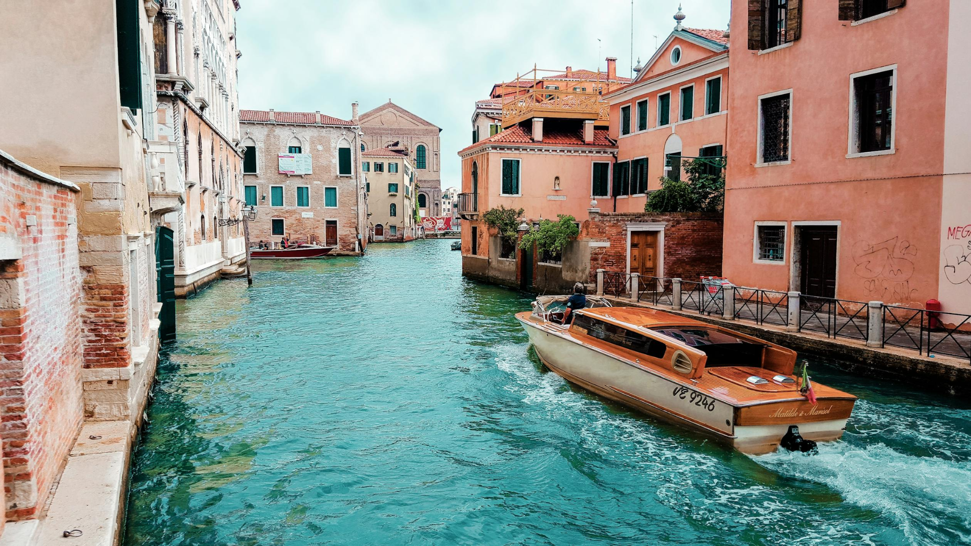 orange-powerboat-between-medium-rise-buildings